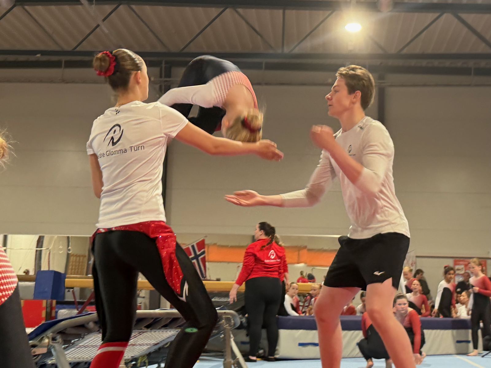 Gymnast gjør salto med hjelp fra trener